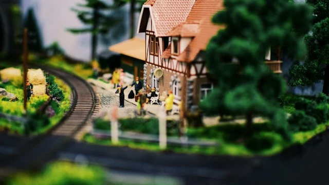 Miniature train station with railway tracks, a small train, and surrounding buildings