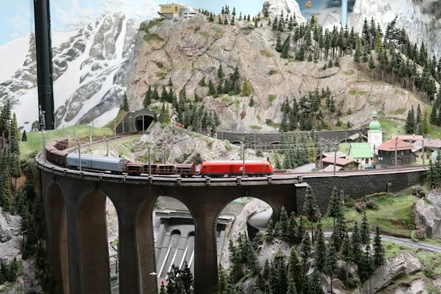 Miniature winter train scene with a railway bridge and snow-covered landscape